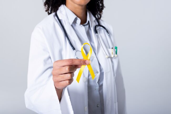 Doctor holding yellow sarcoma ribbon.